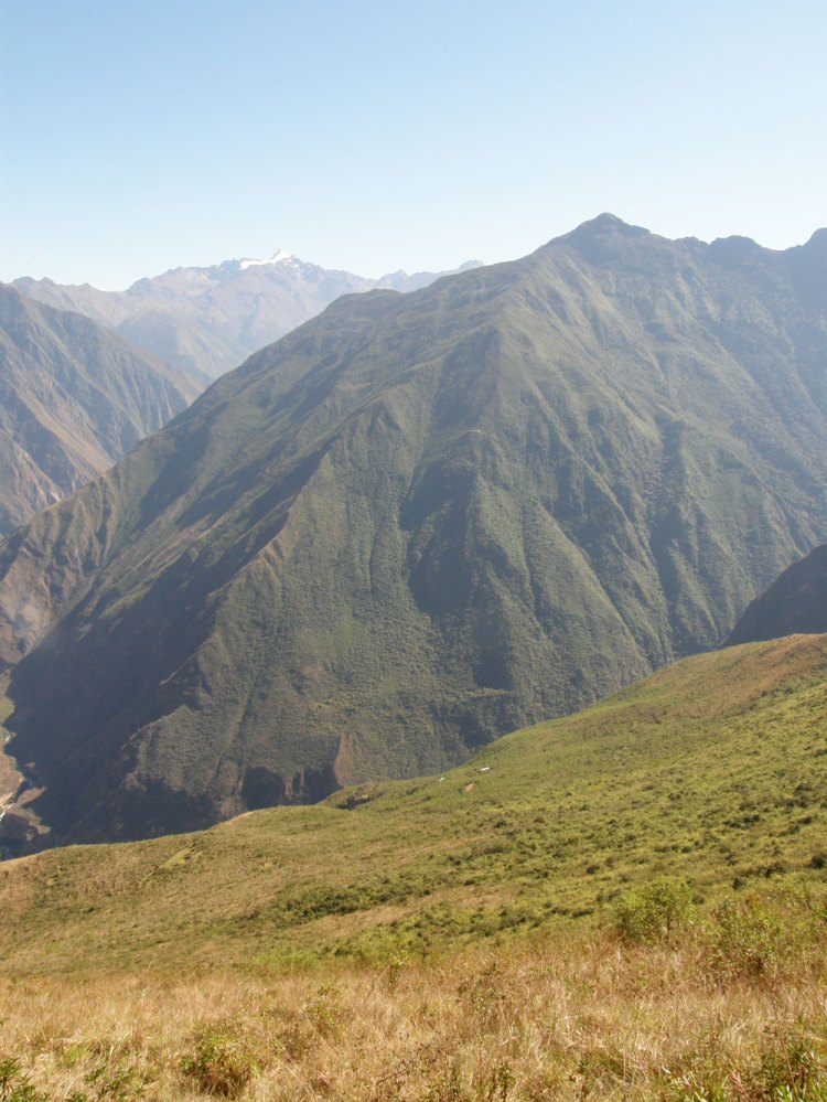 ¿Se ve la casita hasta la que se tiene que caminar este día?El Río Blanco o Yuracmayo queda al fondo de esta quebrada. La bajada es inmensa y la subida que venía peor. En la montaña verde de en frente, justo al medio en una cornisa que sobre sale, se distingue una mancha blanca. Es el techo de calamina de la casita en Maizal, a donde tendríamos que llegar a domir. Cuando tomé la foto pensaba que no la hacía ni en moto porque  sólo el campamento de los arqueólogos me pareció lejísimos (en la ladera donde estamos, abajo).